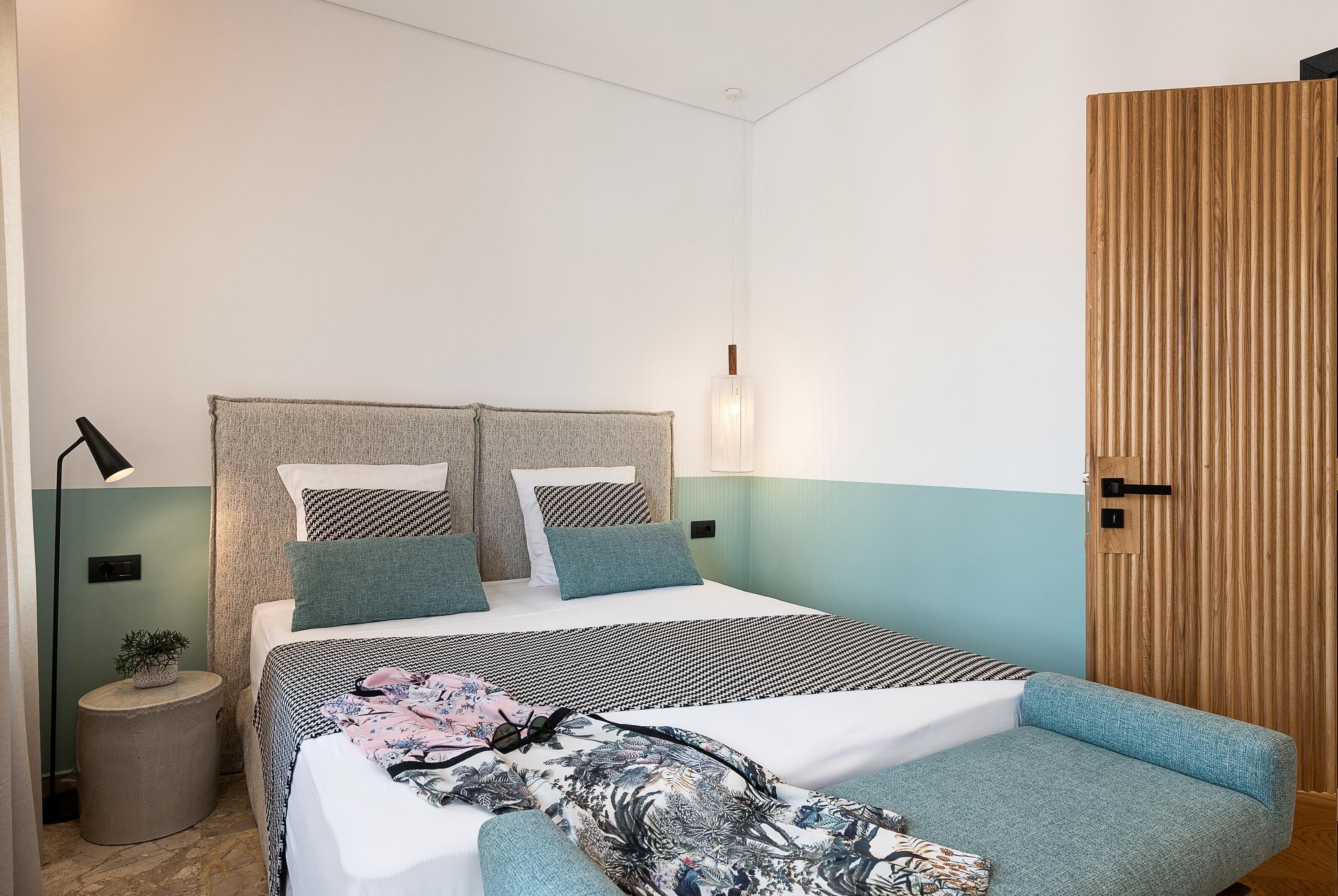 A modern bedroom with a bed, bedside tables, a lamp, and a wooden wardrobe.