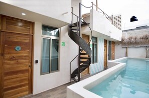 A modern building with a spiral staircase, a pool, and wooden doors. - Hotel downtown private room with pool. (Cancún)