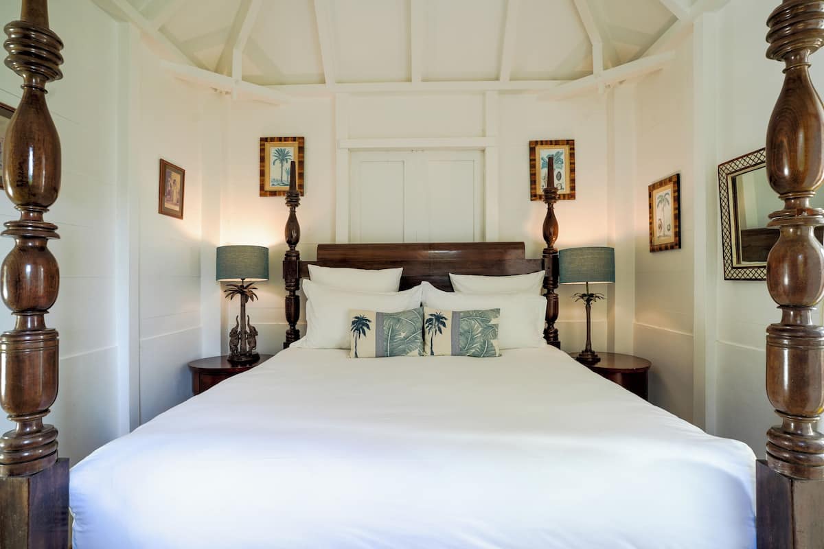 Een groot bed met een houten hoofdeinde, twee nachtkastjes met lampen en lijstjes met foto's aan de muur.