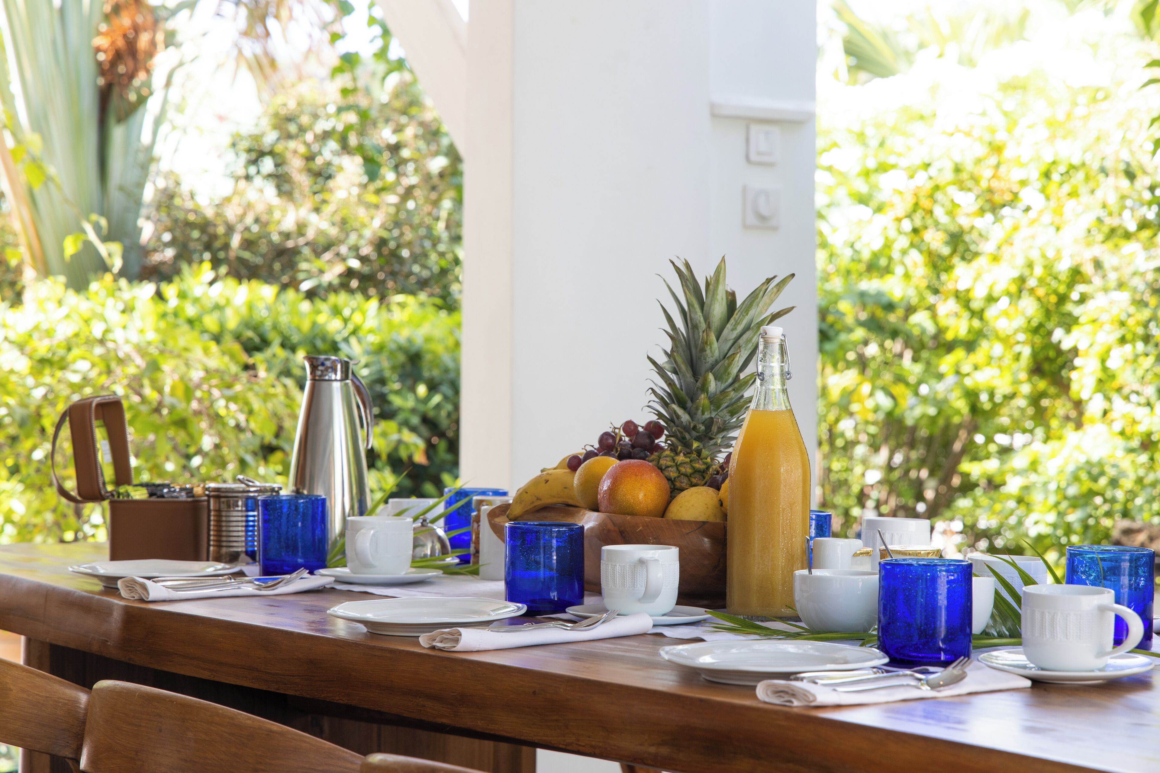 Een ontbijttafel gedekt met fruit, koffiekopjes en een fles sap.