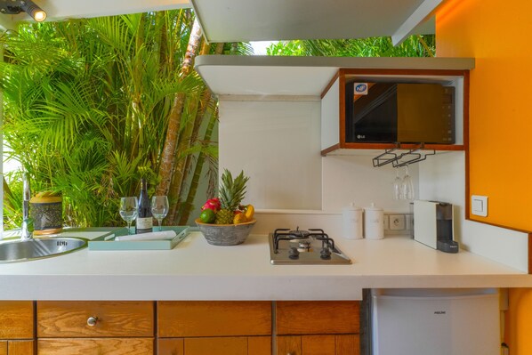 Una cocina con estufa a gas, pileta y un bol de fruta.