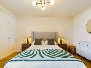 A bedroom with a bed, two bedside tables with lamps, a dresser, and a ceiling light fixture. - Cosy Covent Garden Apartment (London)