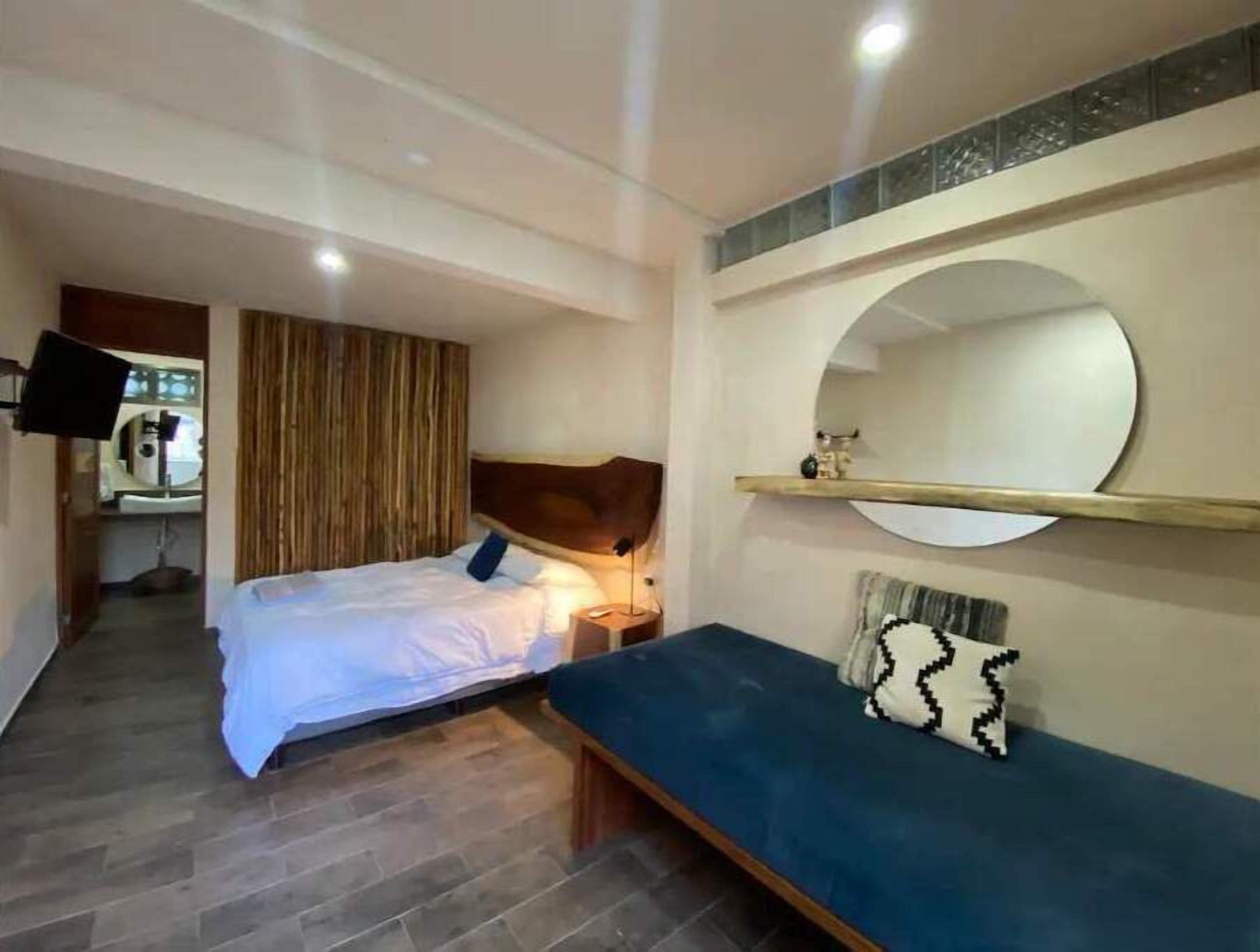 Un dormitorio con cama, mesita de noche y un espejo grande en la pared.