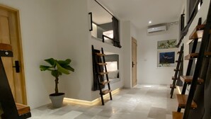 A modern hallway with a potted plant, a wooden bench, and a staircase with a railing. - Wild Monkeys Hostel (Moalboal)