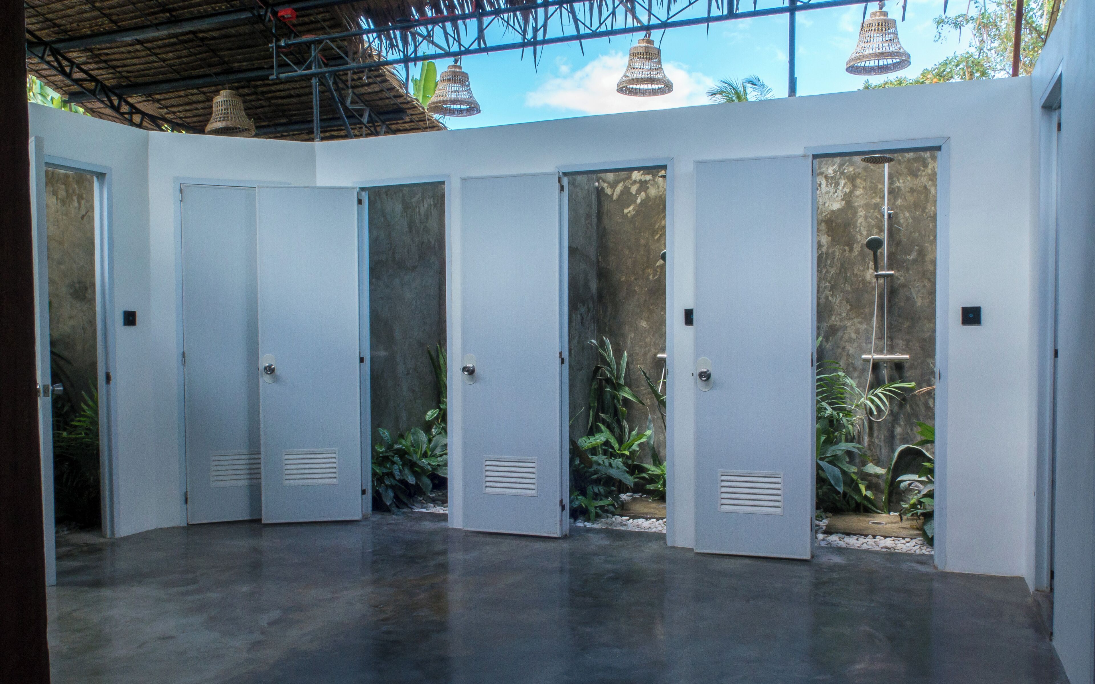 A modern interior with a concrete floor, white doors, and a view of greenery outside.