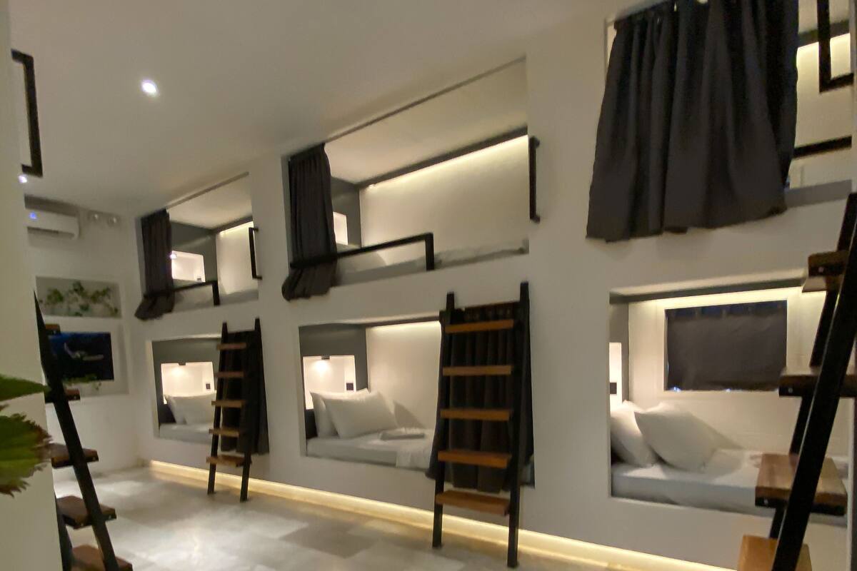 Una habitación de hotel moderna con literas, una escalera y un ventanal grande.