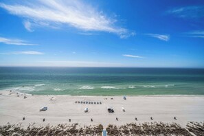 A beach with a clear sky, calm sea, and a few people.
