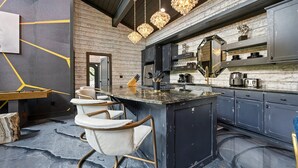 A modern kitchen with a central island, bar stools, and pendant lighting.