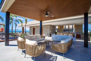 An outdoor lounge area with wicker furniture, a stone wall, and a view of the ocean.