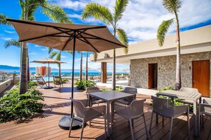 Eine Außenpatio mit Tischen und Stühlen, einem Pool und Blick auf den Ozean.