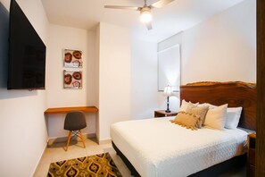 Un dormitorio con una cama, un escritorio, una silla, una lámpara y un ventilador de techo.