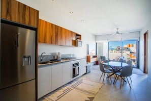 A modern kitchen with a built-in oven, a refrigerator, and wooden cabinets.