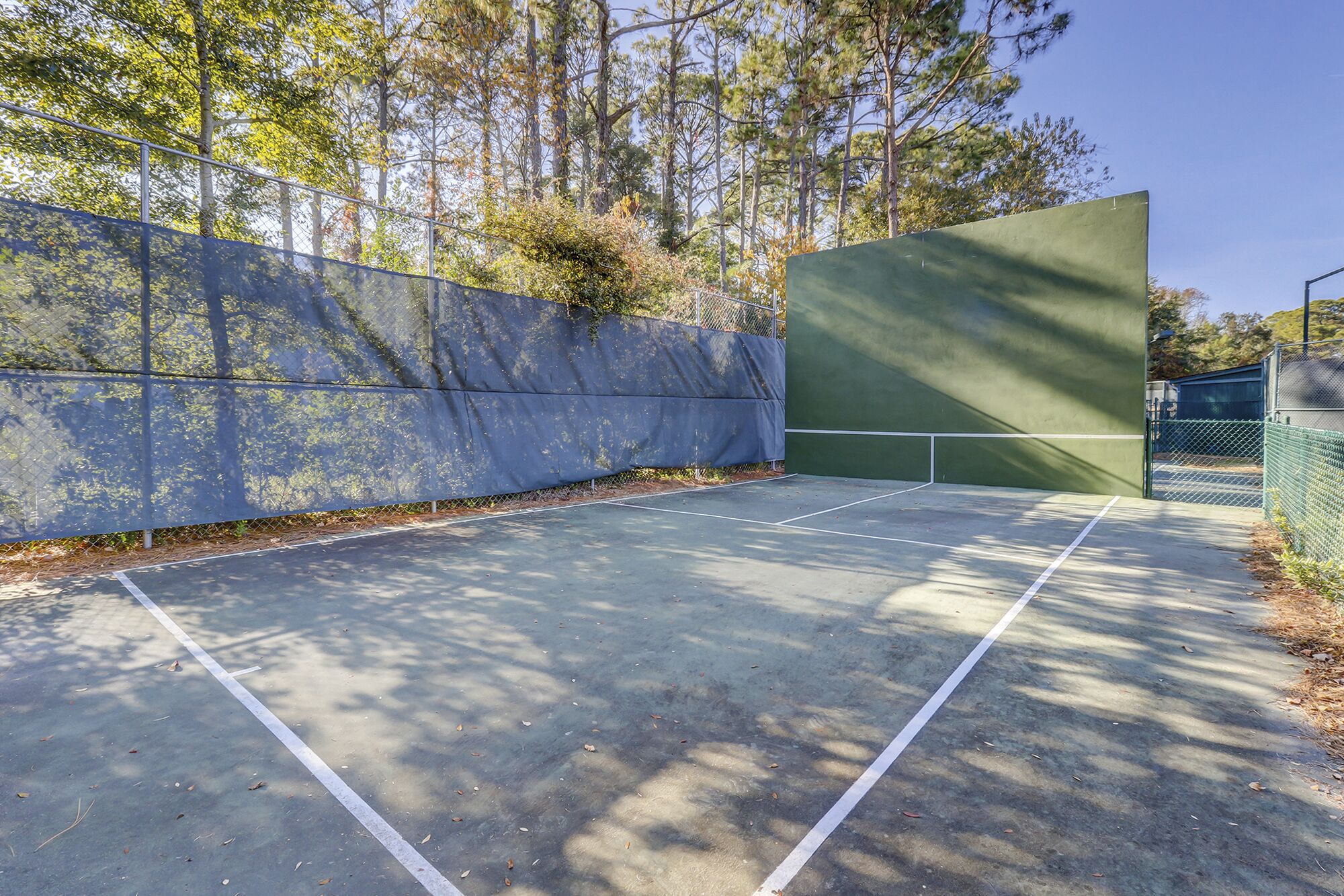 An outdoor tennis court with a green surface and white boundary lines.