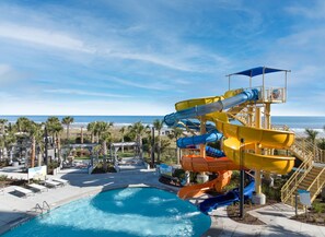 A water park with multiple slides, a pool, and a beach view.
