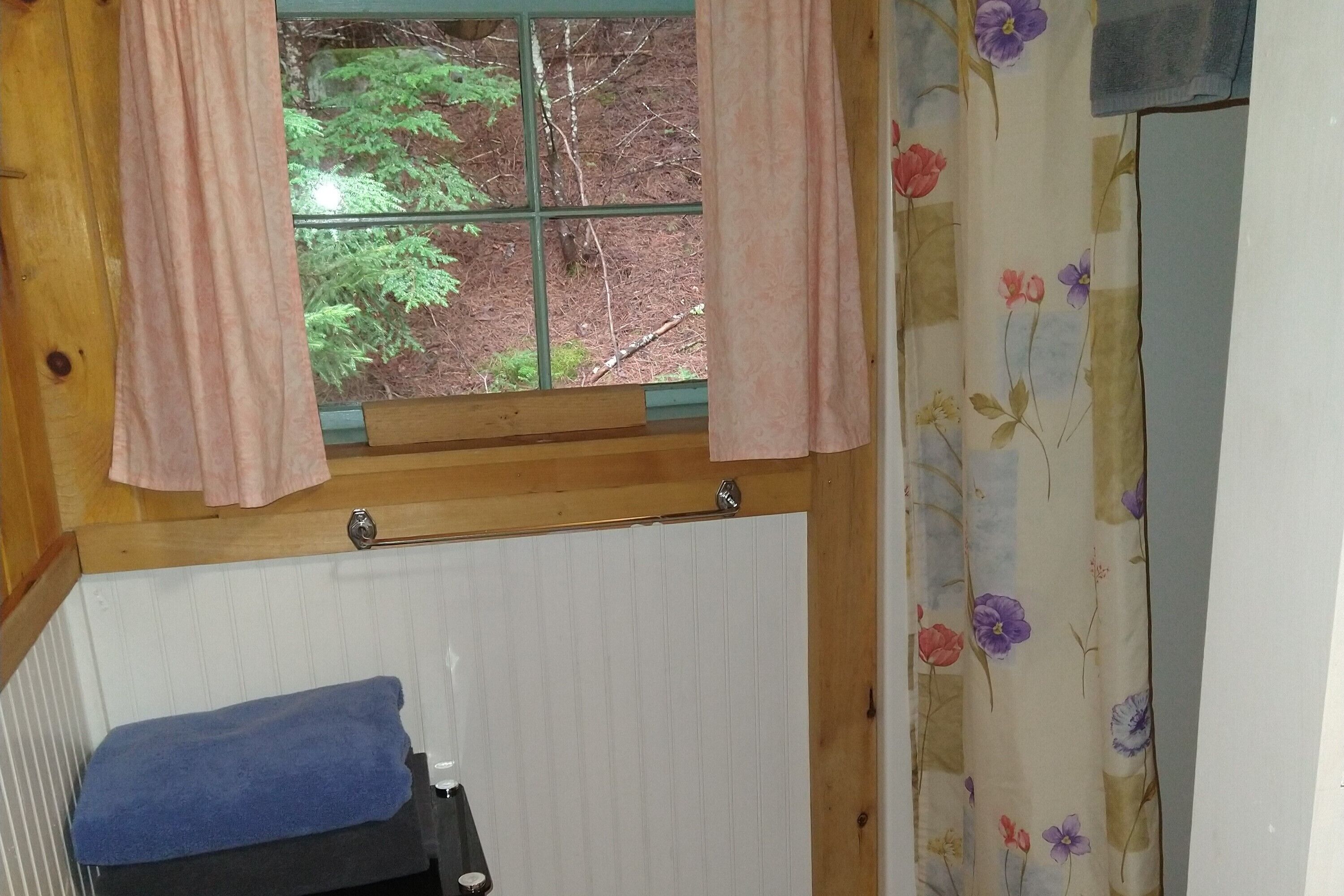 A room with a window, a radiator, a towel, and a curtain with a floral pattern.
