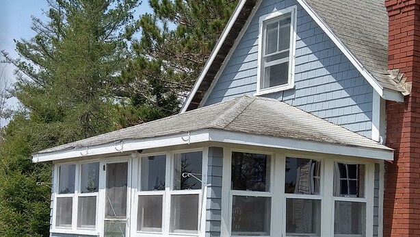A corner building with a blue exterior, white window frames, and a small porch with steps.