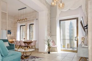A spacious living room with a teal sofa, a round coffee table, and a dining area with pink chairs. - Luxury Apartment (Jerusalem)