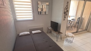 Une petite chambre moderne, équipée d’un lit, d’une télévision et d’une petite table.