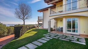 Une maison moderne avec un chemin de pierre menant à un patio, un balcon et offrant une vue sur la mer.