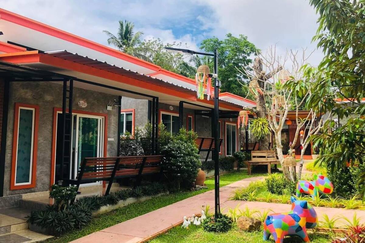 A building with a red roof and a covered walkway. There are colorful animal sculptures in the garden.