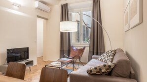 Moderni olohuone, jossa on sohva, sohvapöytä ja televisio.