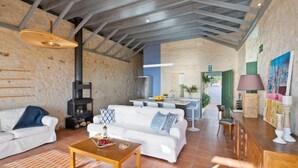 A spacious living area with a fireplace, white sofas, a wooden coffee table, and a kitchen in the background. - Villa Mediterranea – Beachside Escape for Slow Living with Private Heated Pool (Livadia)