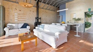 A modern interior with two white sofas, a wooden coffee table, a black fireplace, and a kitchen area with a bar. - Villa Mediterranea – Beachside Escape for Slow Living with Private Heated Pool (Livadia)
