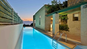 A swimming pool with a clear blue water surface, surrounded by a stone wall and a covered area with a pergola. - Villa Mediterranea – Beachside Escape for Slow Living with Private Heated Pool (Livadia)