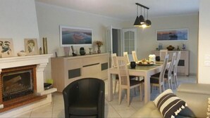 Un salon avec une cheminée, un coin repas et une cuisine.