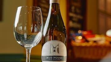 Eine Flasche Mud House Sauvignon Blanc und ein leeres Weinglas auf einem Tisch.