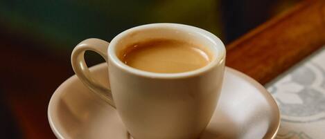 A white cup of coffee on a saucer on a wooden table.