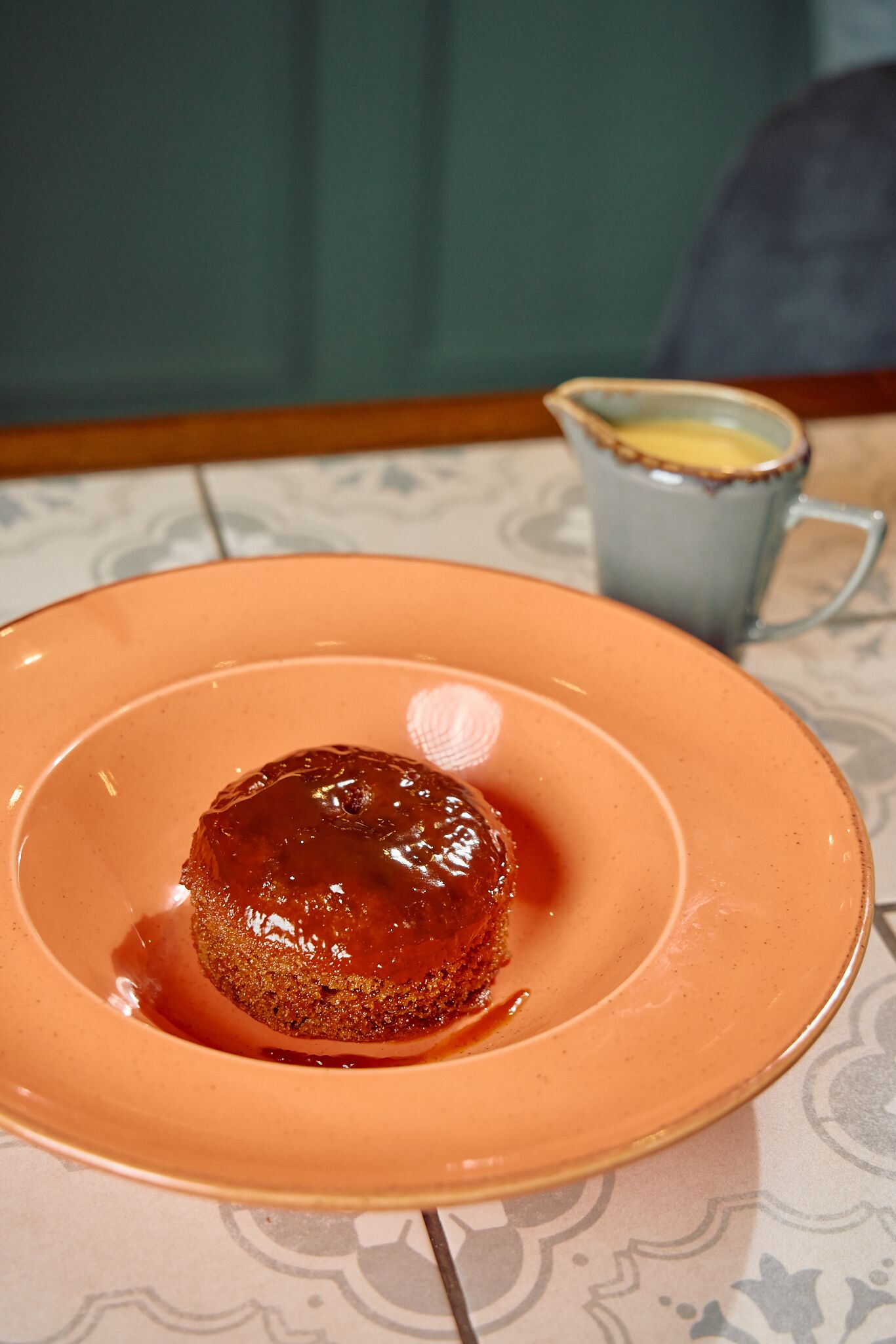 A dessert on a plate with a cup in the background.