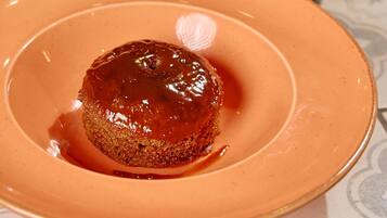 A dessert on a plate with a cup in the background.
