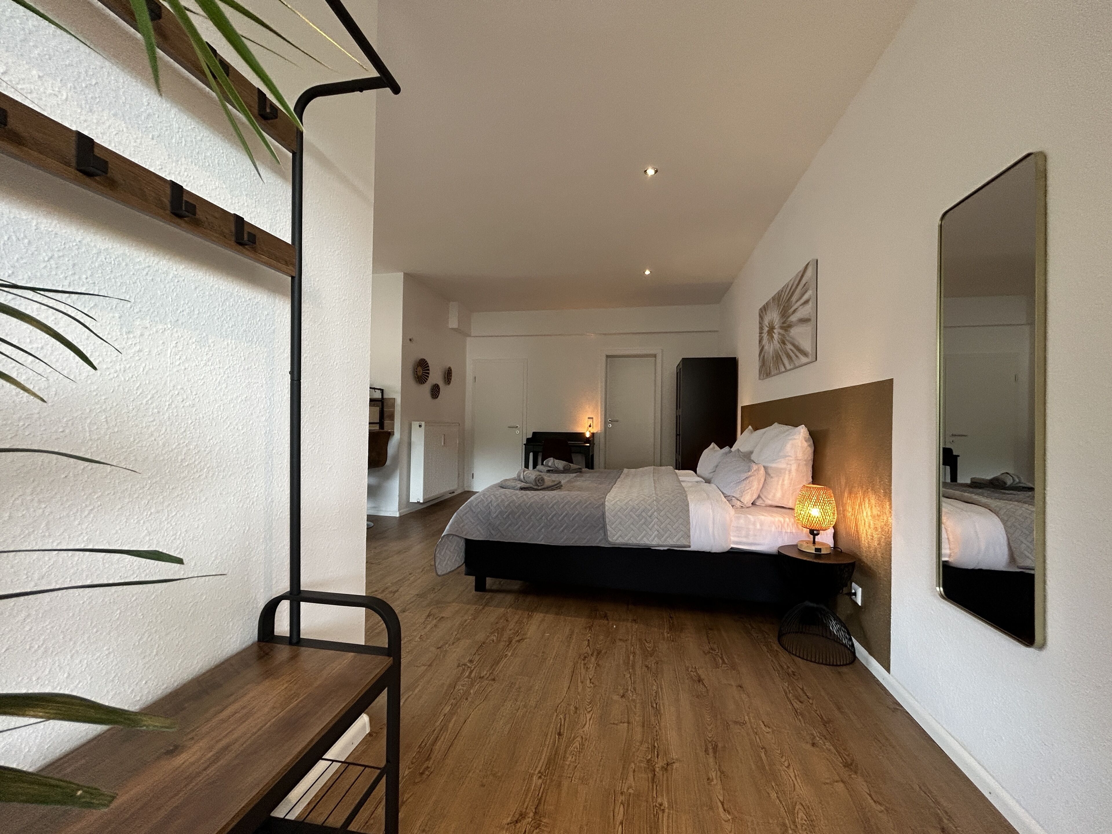 Une chambre à coucher moderne avec un grand lit, une table de chevet et un miroir.