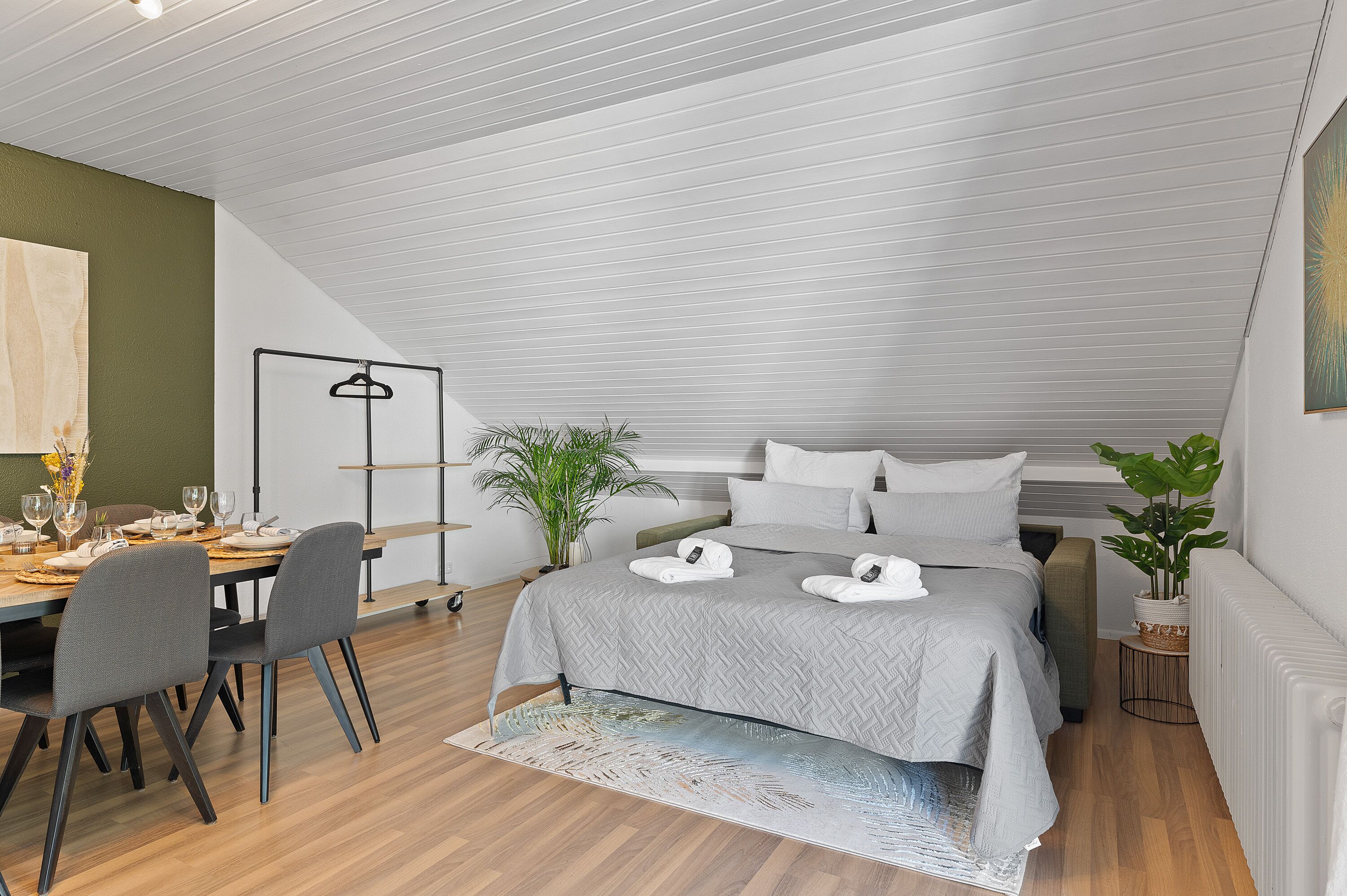 Ein modernes Schlafzimmer mit Bett, Nachttischen, einem Schreibtisch mit Stühlen und einem Essbereich.