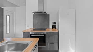 A modern kitchen with a stainless steel sink, a built-in oven, a white Bosch refrigerator, and a wooden countertop.