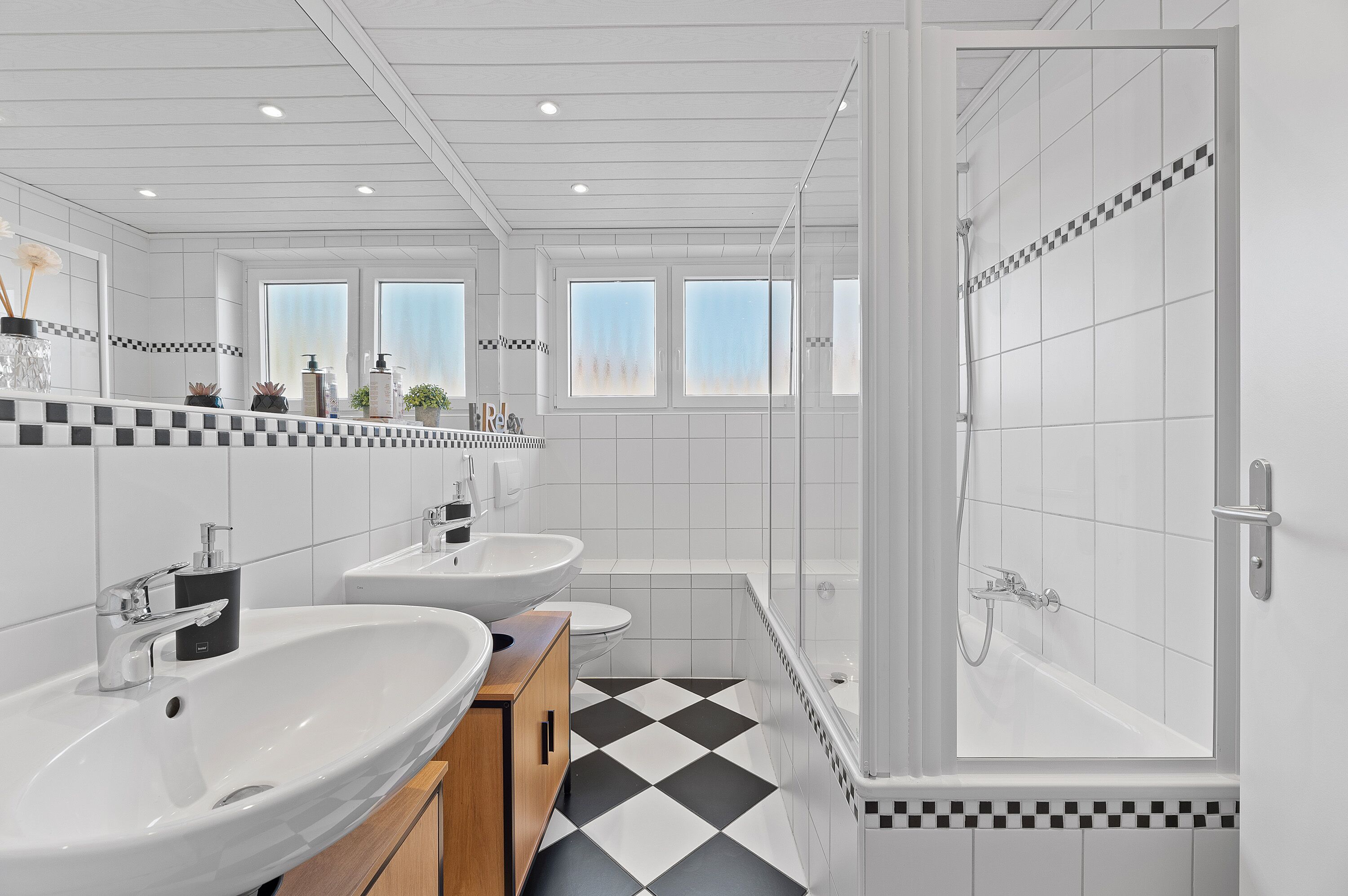 A modern bathroom with two sinks, a toilet, and a shower.
