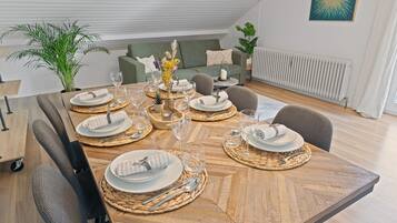 Zona pranzo con tavolo in legno apparecchiata per sei persone, circondata da sedie.