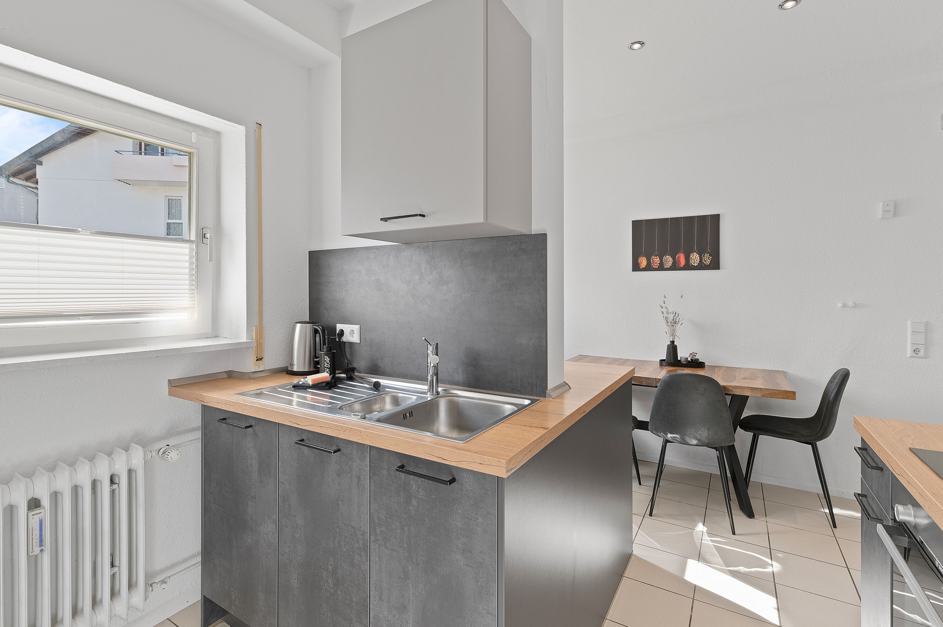 A modern kitchen with a built-in sink, wooden countertop, and grey cabinets.