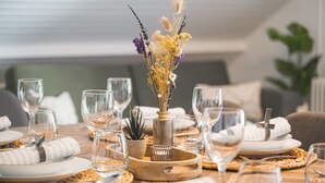 A dining table set with plates, glasses, and a centerpiece of dried flowers and greenery. - LUMIFLATS (Mahlberg)
