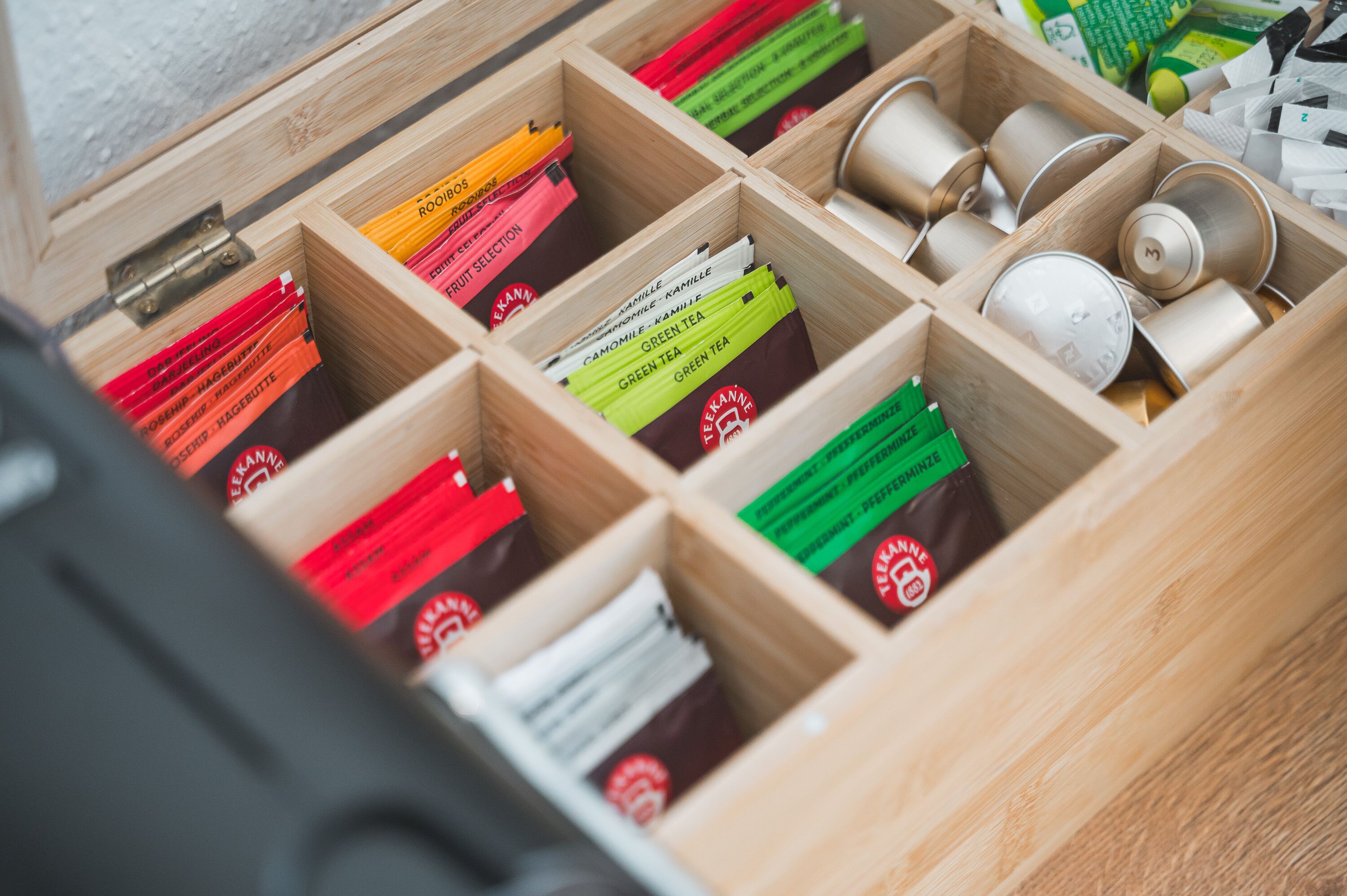 A wooden drawer with compartments containing various tea bags and tins.