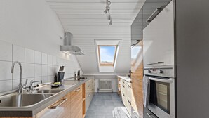 A modern kitchen with a skylight, stainless steel appliances, and wooden cabinets. - LUMIFLATS (Mahlberg)