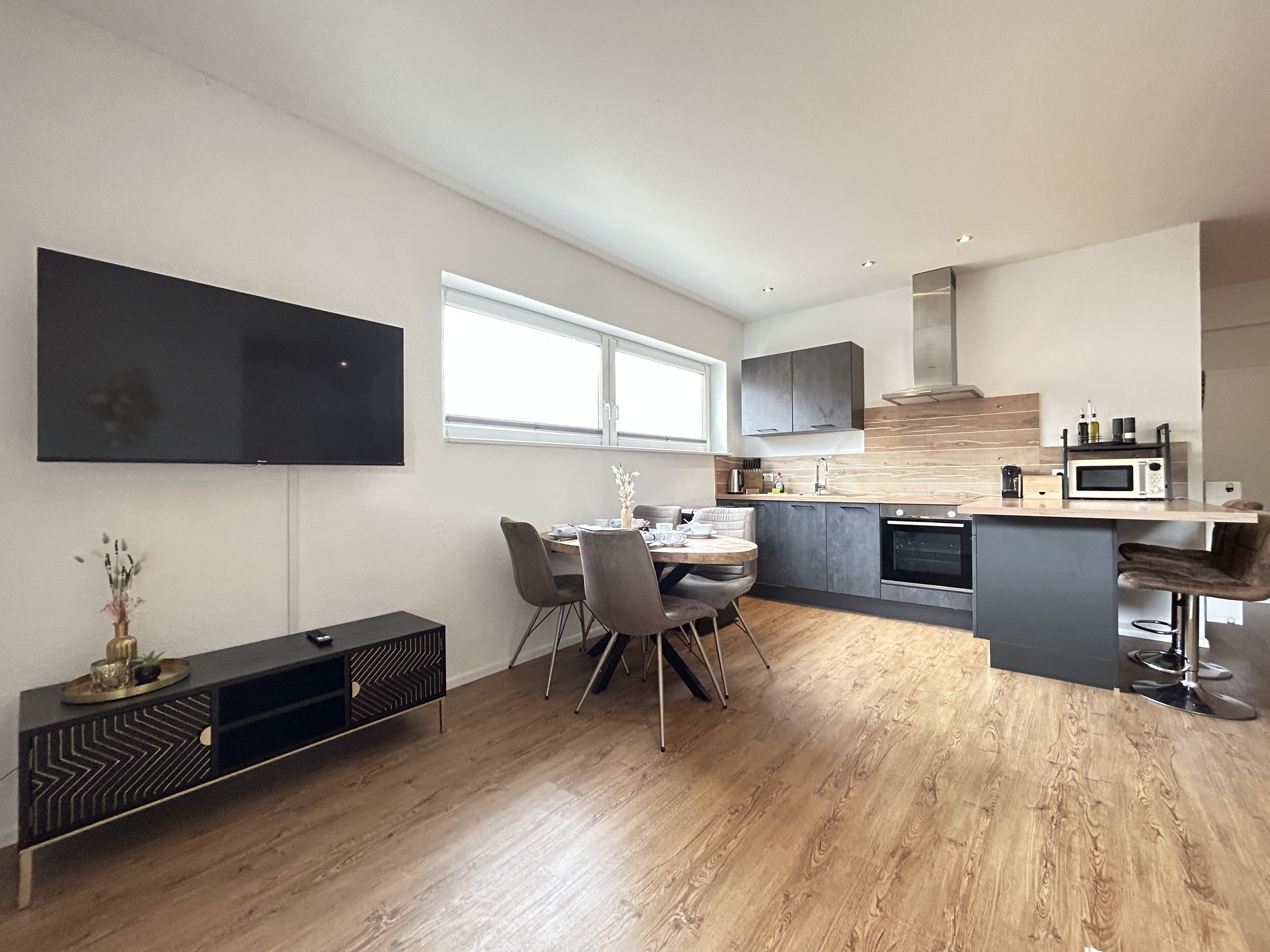 Una cocina moderna con comedor, suelo de madera y electrodomésticos integrados.