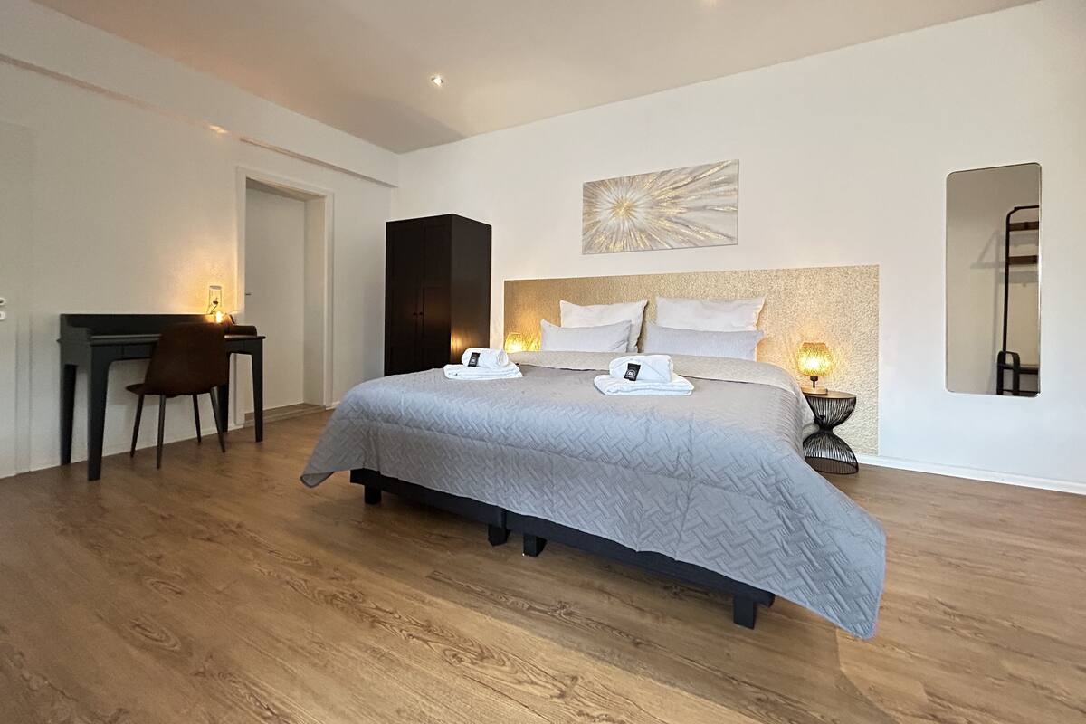 Un dormitorio moderno con una cama grande, un escritorio y una silla.