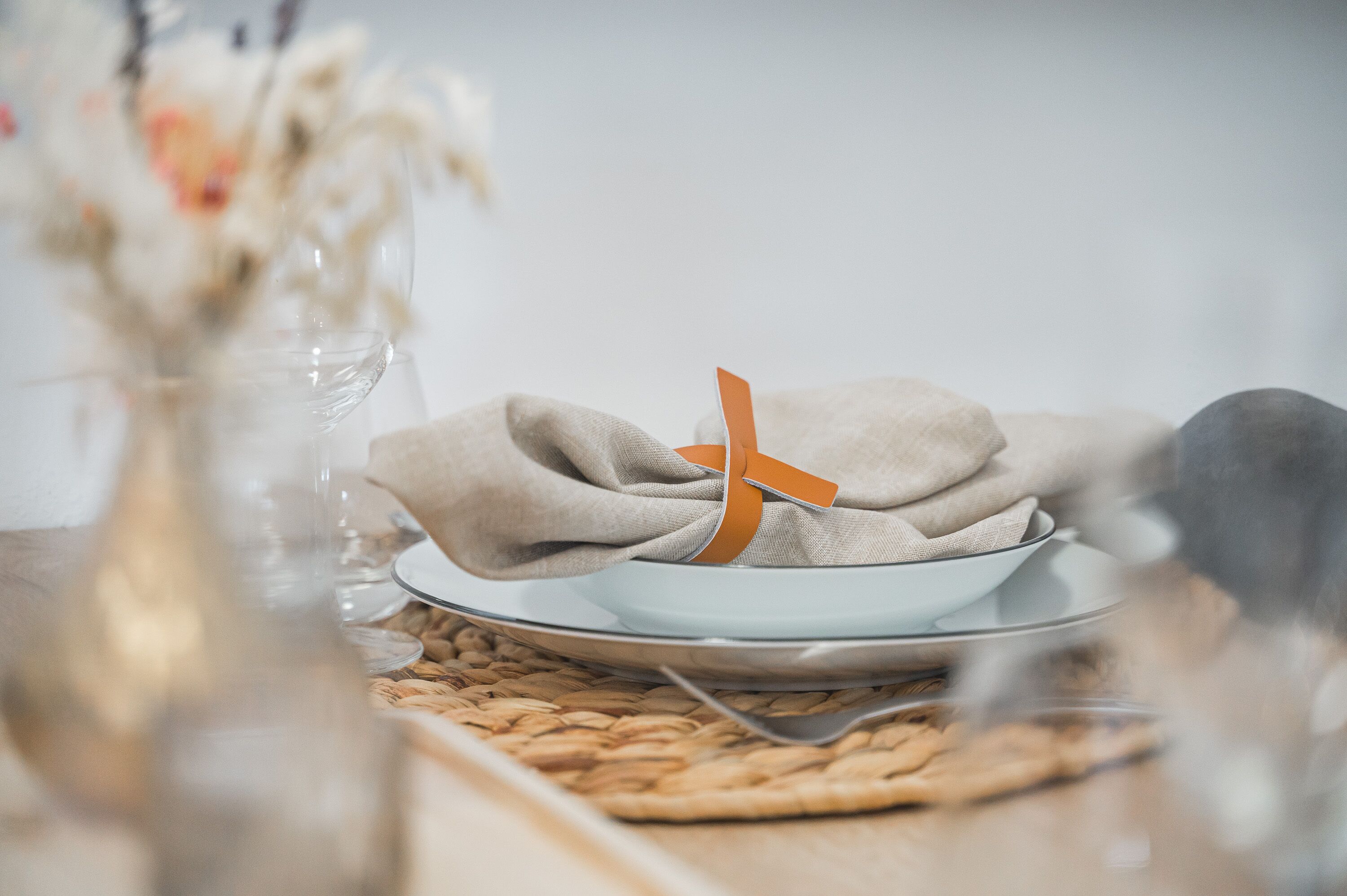 Una mesa dispuesta con un bol, un plato y una servilleta atada con un lazo naranja.