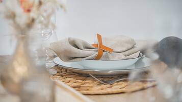 Une table dressée avec un bol, une assiette et une serviette attachée avec un ruban orange.