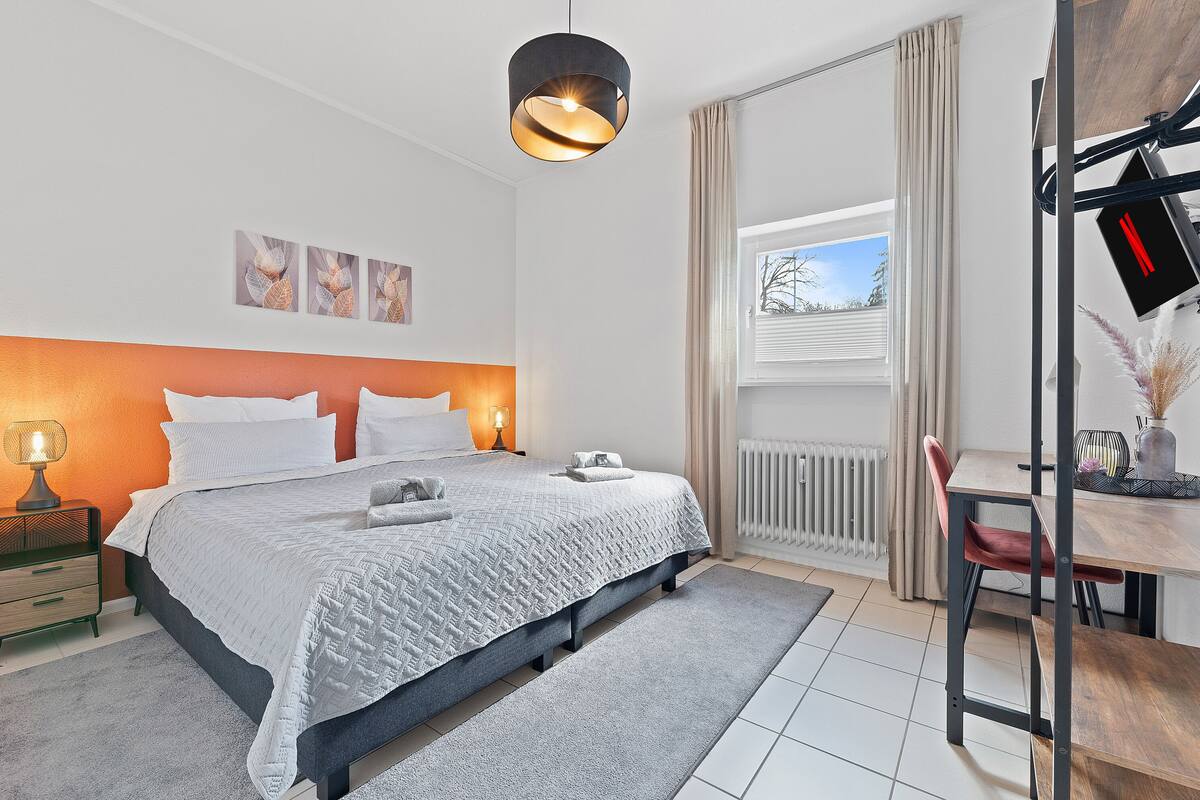 Un dormitorio moderno con cama, mesita de noche y escritorio con silla.