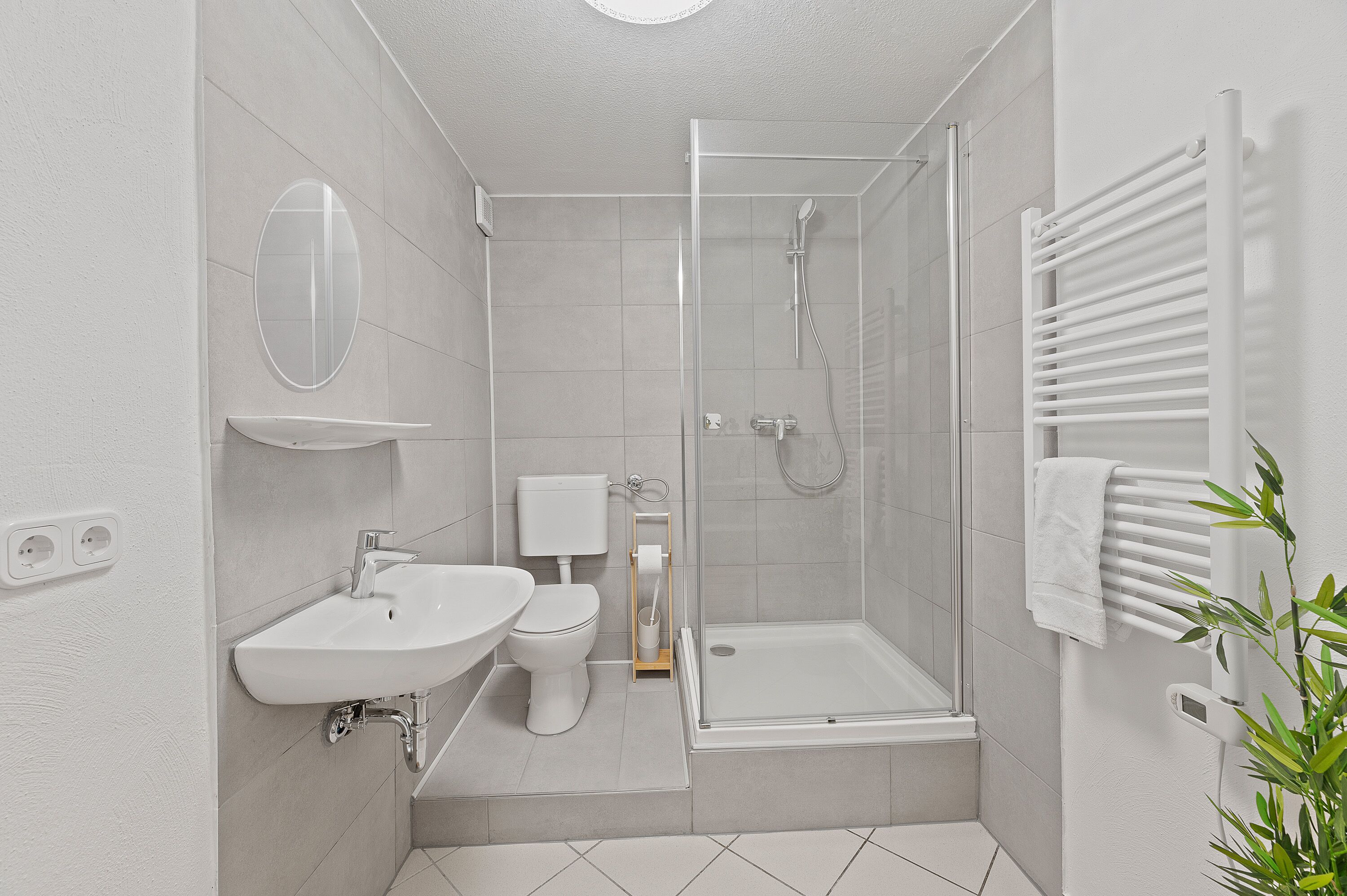 A modern bathroom with a shower, toilet, sink, and towel rack.