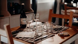 A dining table set with a bottle of wine, wine glasses, and water glasses, with a candle on the table. - Azienda Agricola Saint Hubert (Cantalupo Ligure)