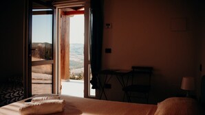 A hotel room with a bed, a small table, a chair, and a view of the outdoors. - Azienda Agricola Saint Hubert (Cantalupo Ligure)